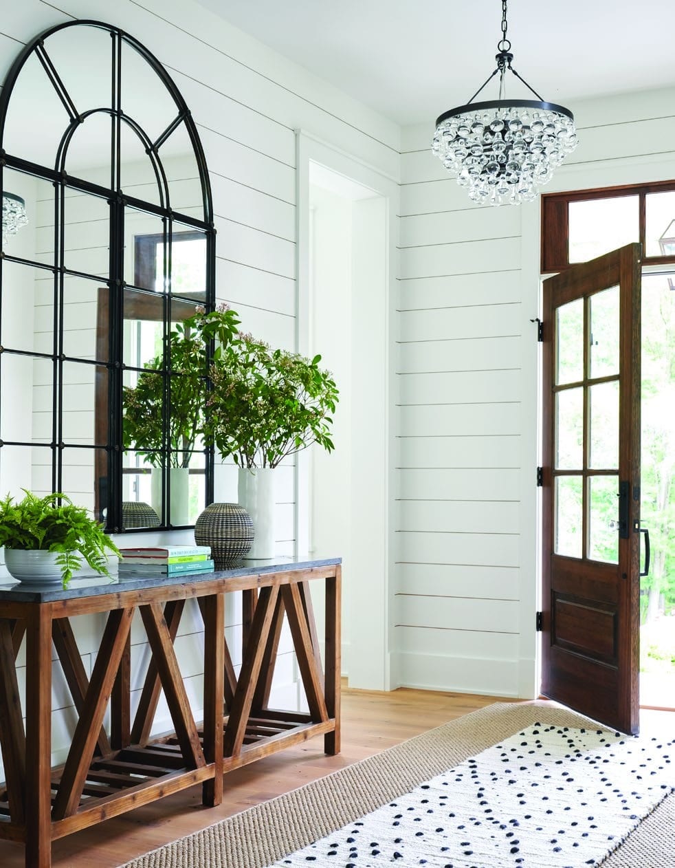 The Huckleberry foyer: a black arched window, a console and the front door beyond